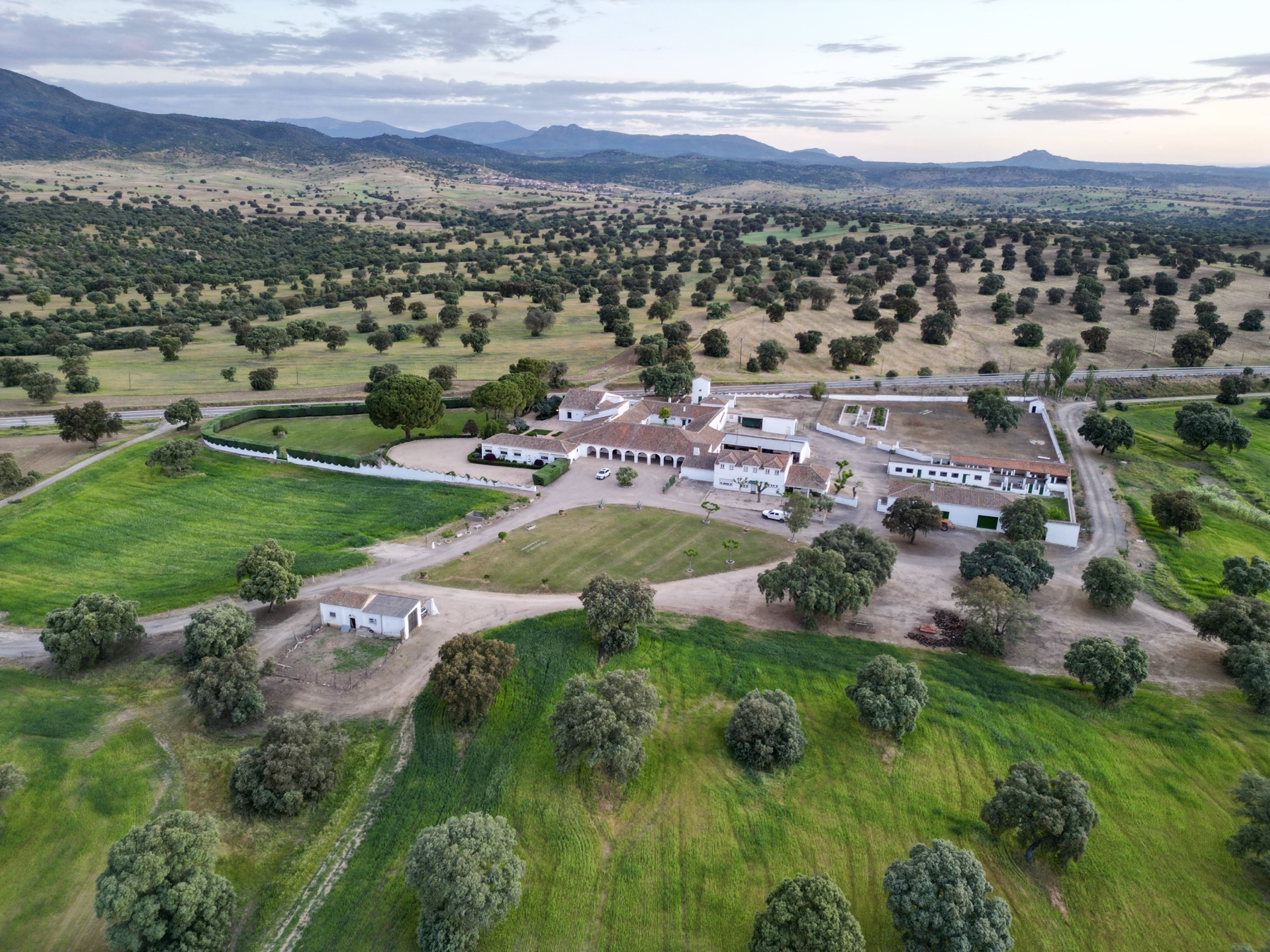 Vista aérea de la casa principal de La Ronca al amanecer, con dehesa y montañas al fondo